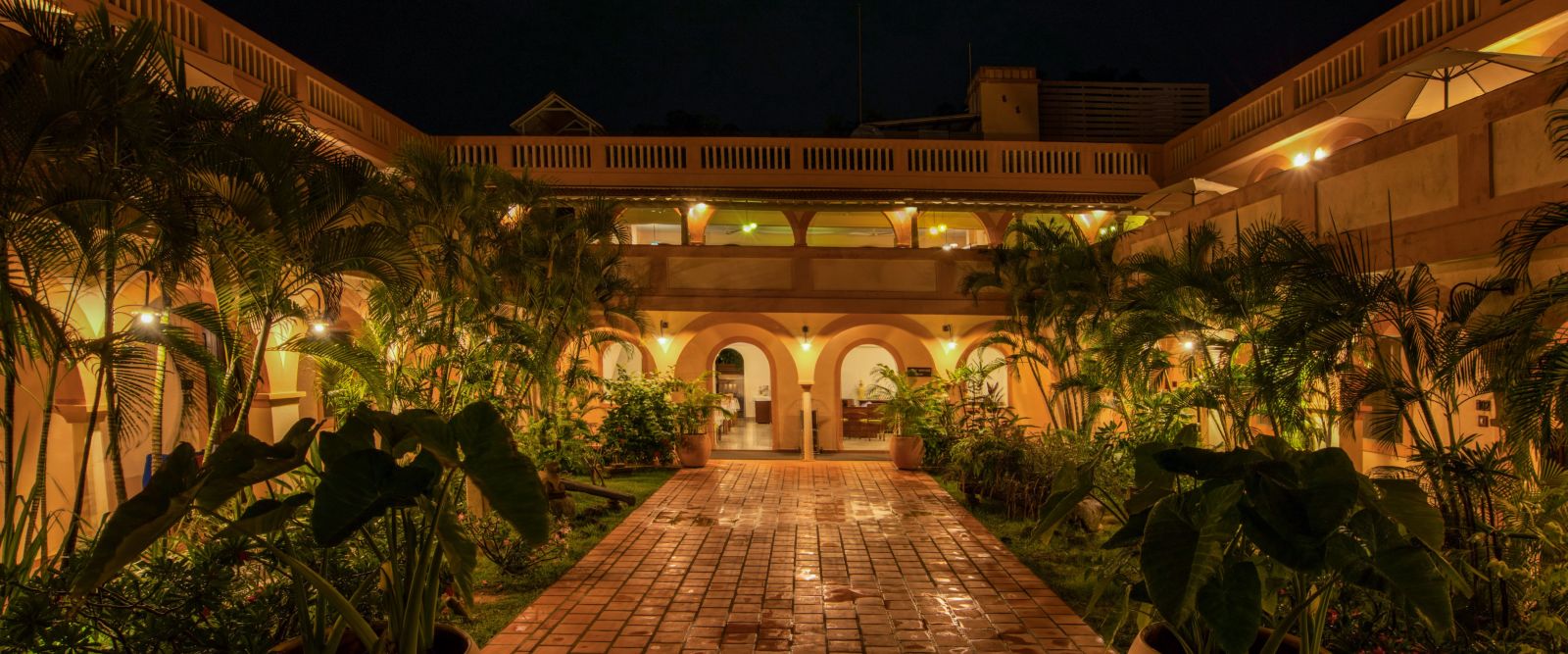 Resort corridor during night time with plants and lights.