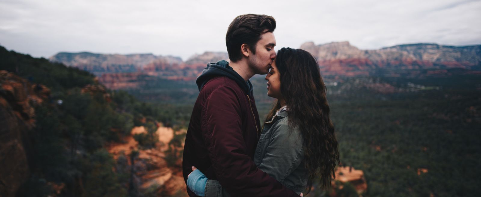 A man kisses his girlfriend s forehead as they stand overlooking the mountains - best resort in Rishikesh for couples