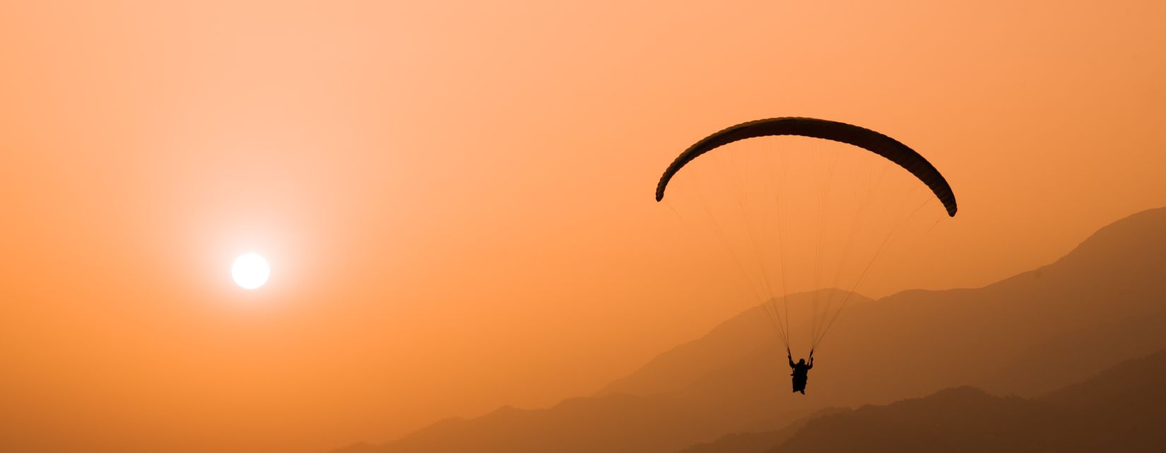 an image of a person paragliding during sunset in a place surrounded by mountains and trees  @ @ Lamrin Norwood Green, Palampur