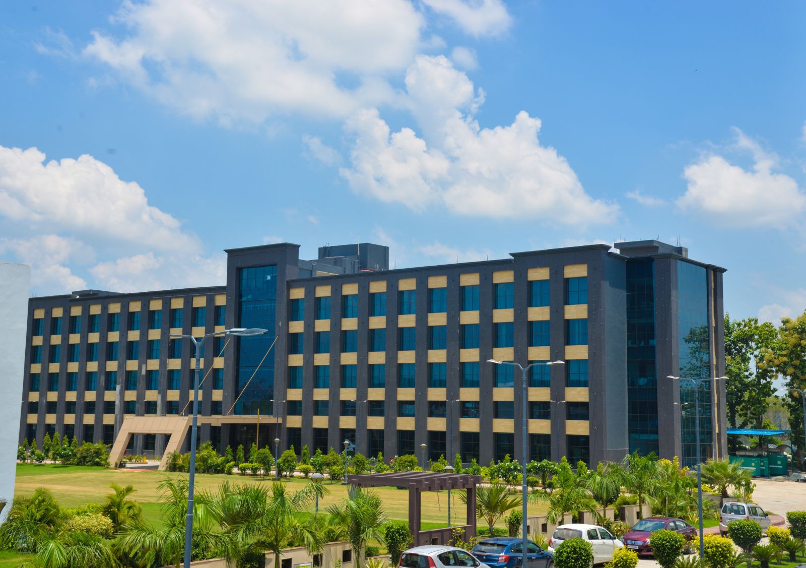 Facade of a big blue building surrounded by a manicured lawn