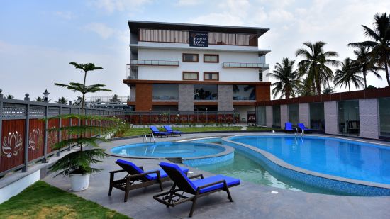 a grand swimming pool in front of resort facade with sunbeds in front and blue sky as the backdrop - Royal Lotus View Resotel