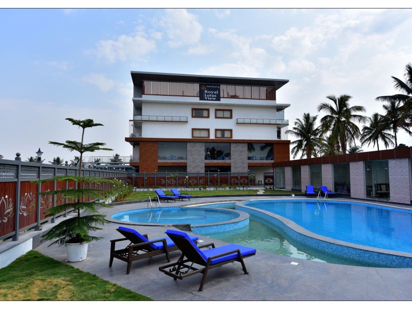 a grand swimming pool in front of resort facade with sunbeds in front and blue sky as the backdrop - Royal Lotus View Resotel