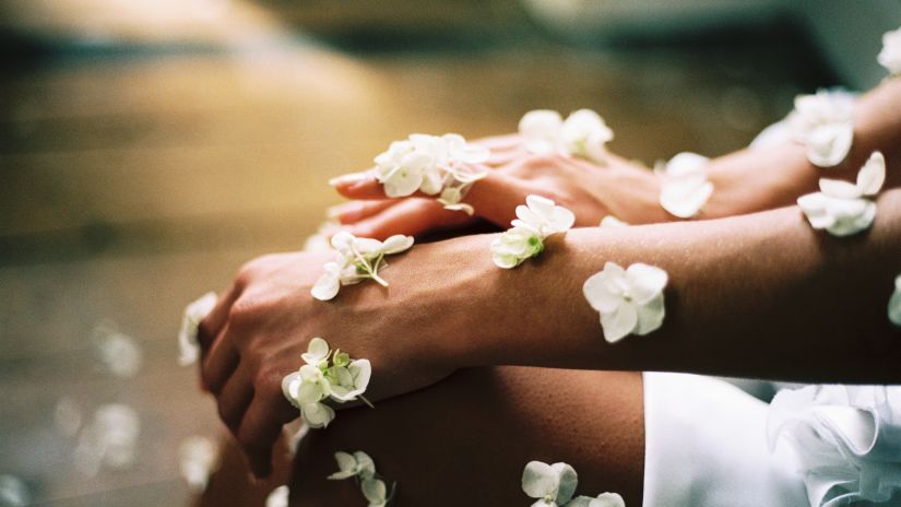 hands with glowing skin and flower petals falling on them