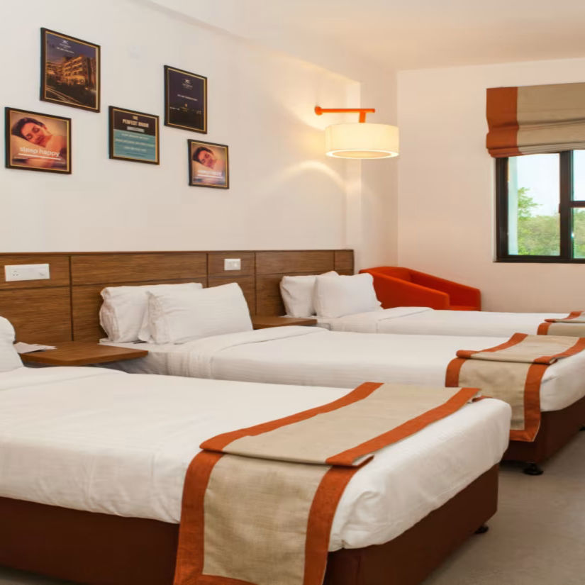 A spacious comfy room with 3 plushy bed, posters on wall, an open window at Max Hotel Prayagraj.