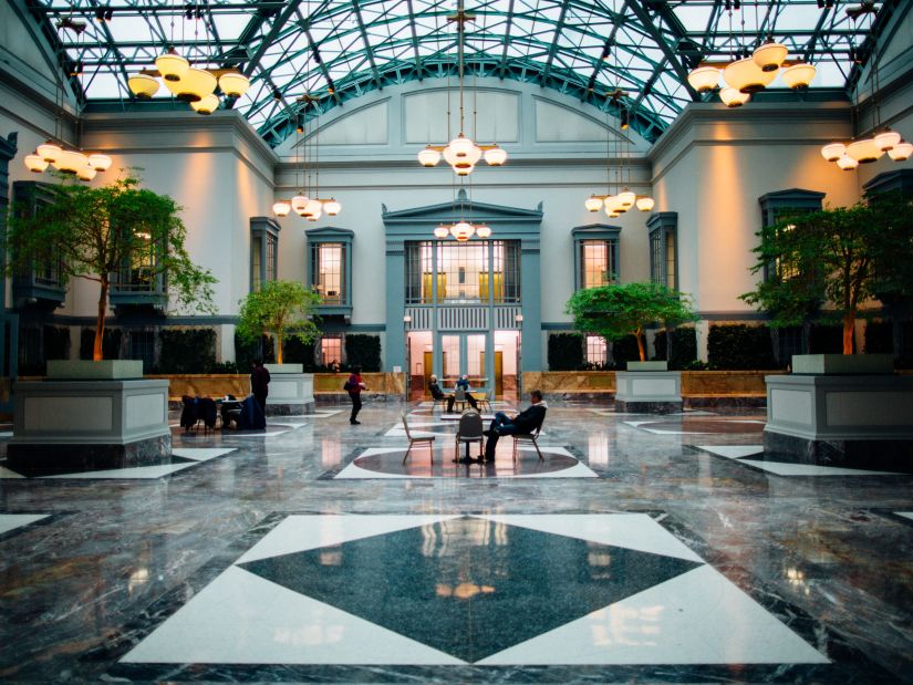 Lobby area of a hotel with a sky roof and marbled flooring