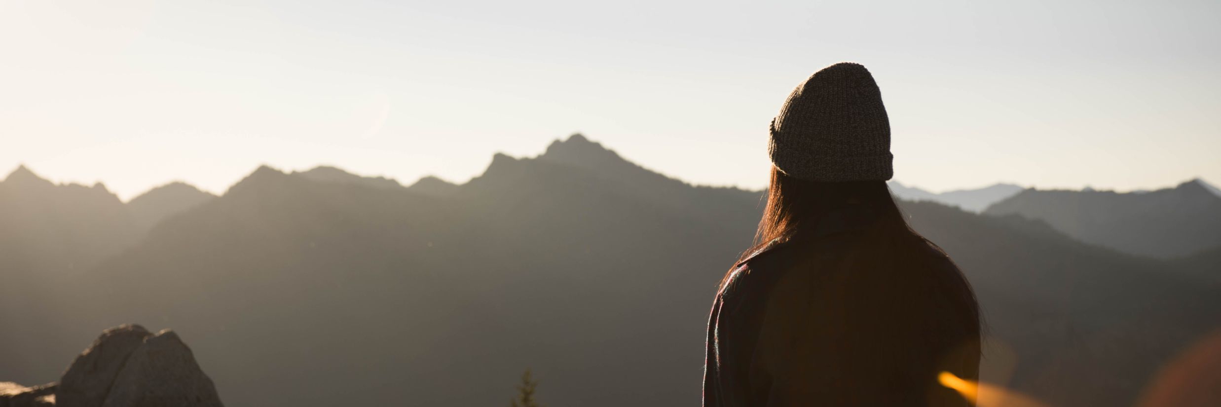 silhouette of woman sitting on a mountain peak