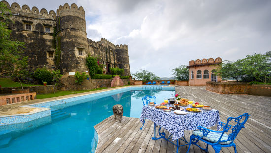 Hill Fort Kesroli 14th Century Alwar - image of a table and chair facing the property's swimming pool