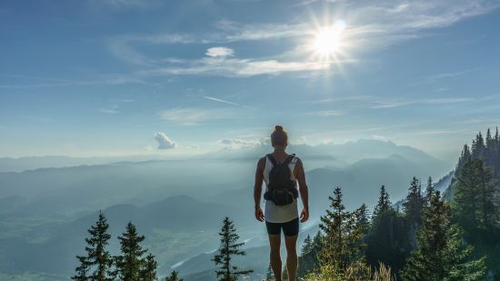 man standing on cliff looking at sunrise