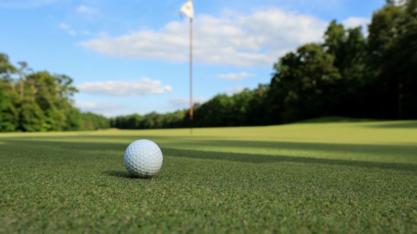 a white golf ball lying on the green golf lawn