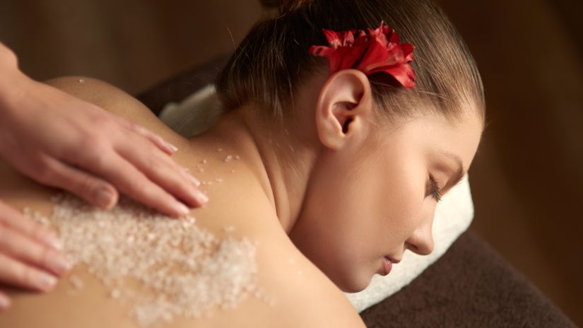 Image of a masseuse applying body scrub on a woman s back