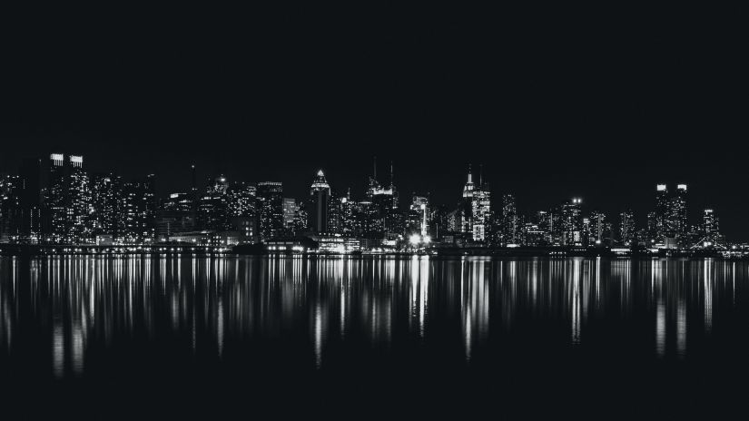 night view of a city in monochrome with the waterbody reflecting the land