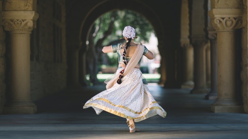 A lady wearing a white saree and spinning around