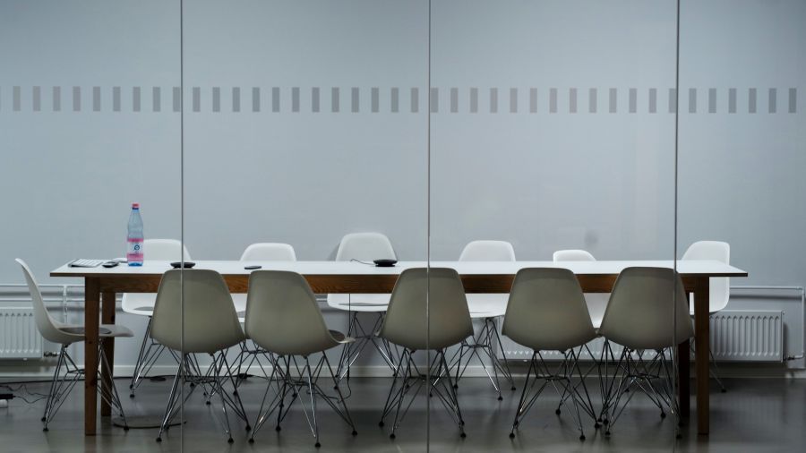 A meeting room with a rectangular table and grey seats