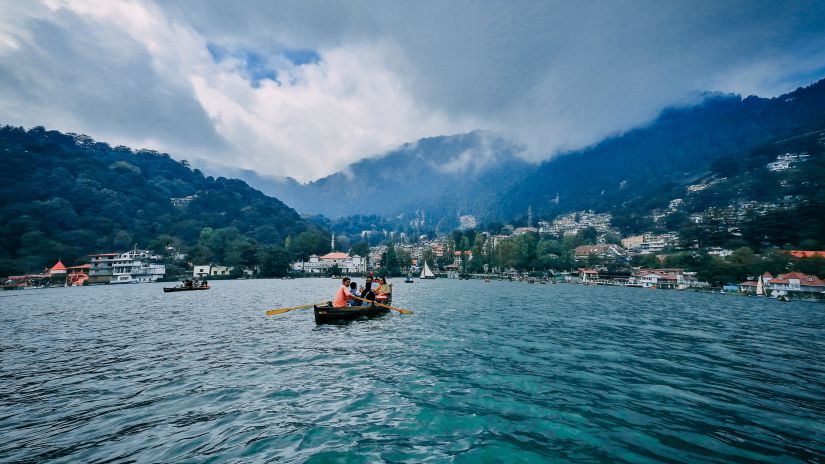 Leisure Hotels - scenic lake surrounded by mountain with a man sailing a boat on it