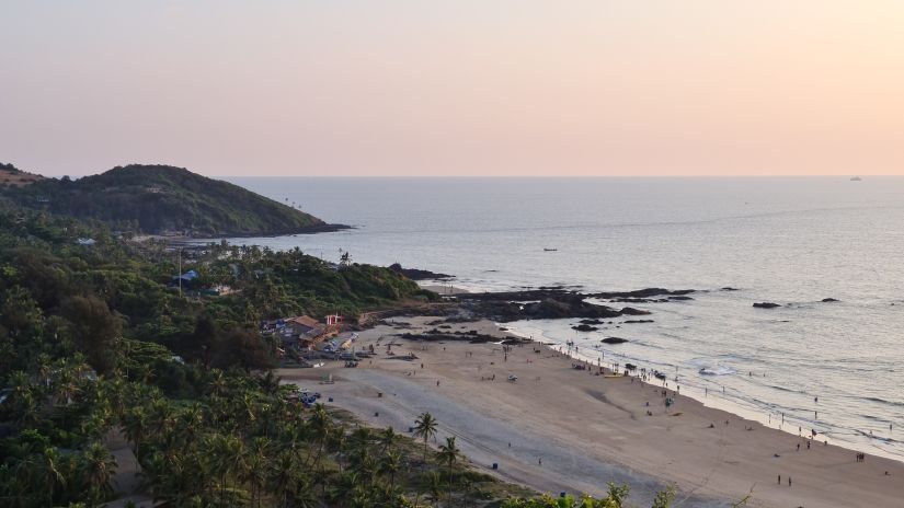 A far view of vagator beach with nature on one side and water on the other