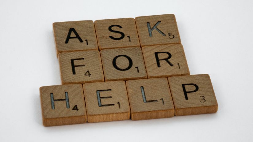 Ask for help written in scrabble tiles on a table