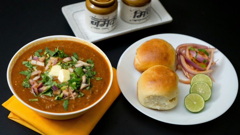 a plate filled with pav (bread), lime slices, and another bowl with bhaji 