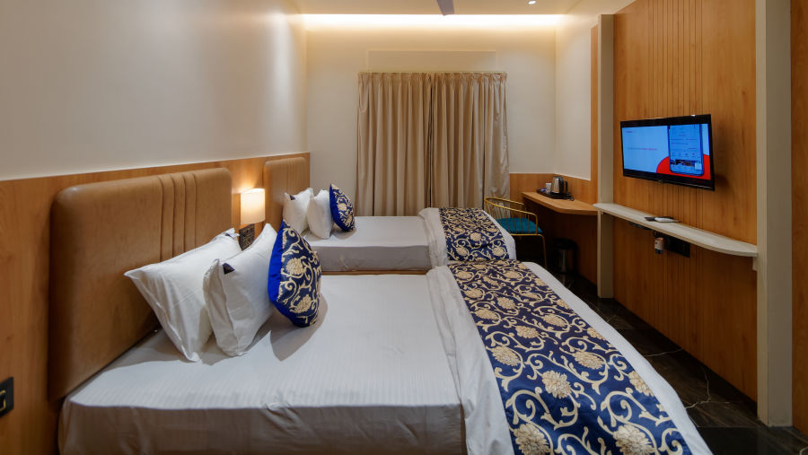 Image of deluxe twin room twin beds with a television in font and ceiling on the wall at Ankit Hotel, Jabalpur