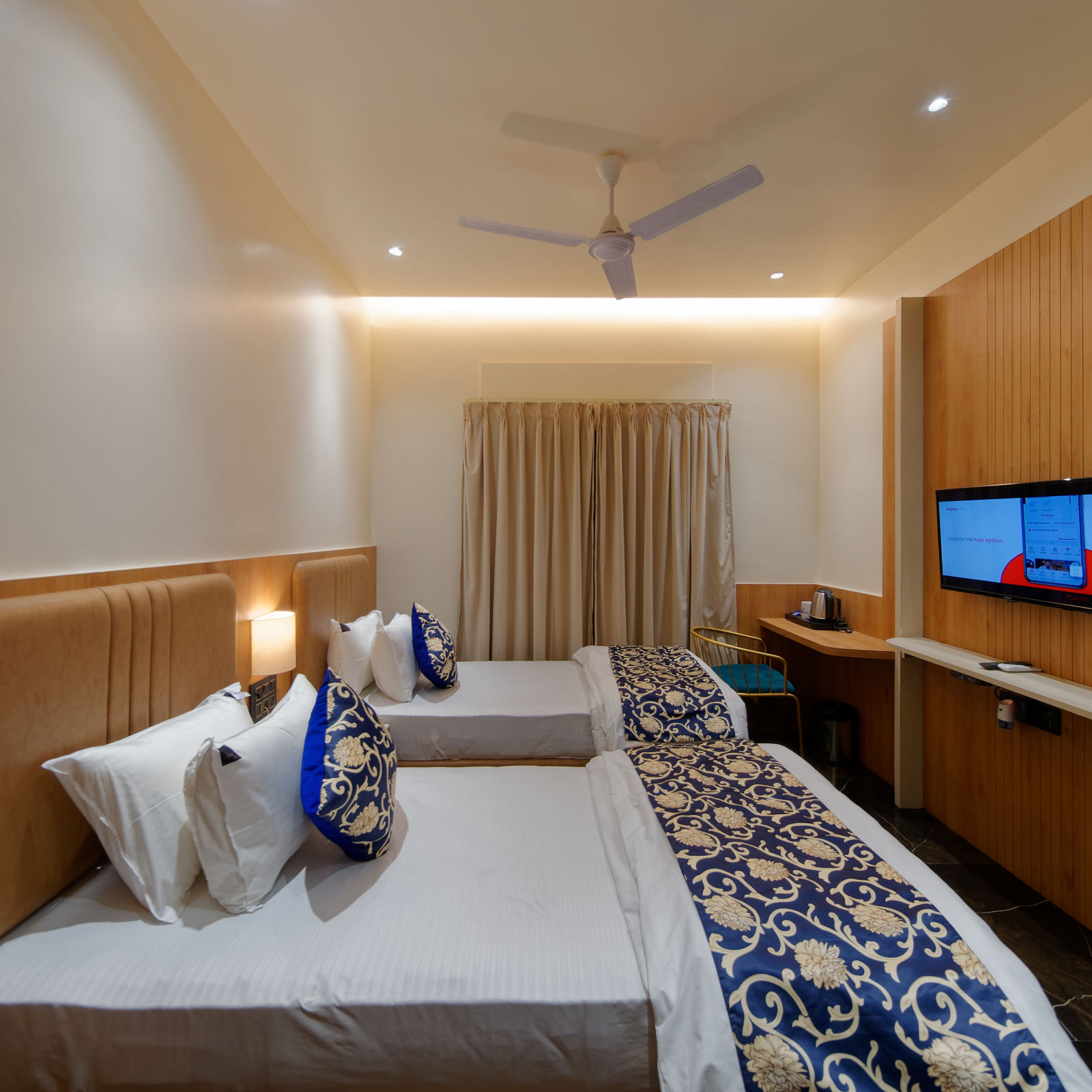 Image of deluxe twin room twin beds with a television in font and ceiling on the wall at Ankit Hotel, Jabalpur