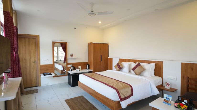 a bedroom with a large bed and a table on one side with wardrobes in the corners- MGM Whispering Wind's, Yelagiri