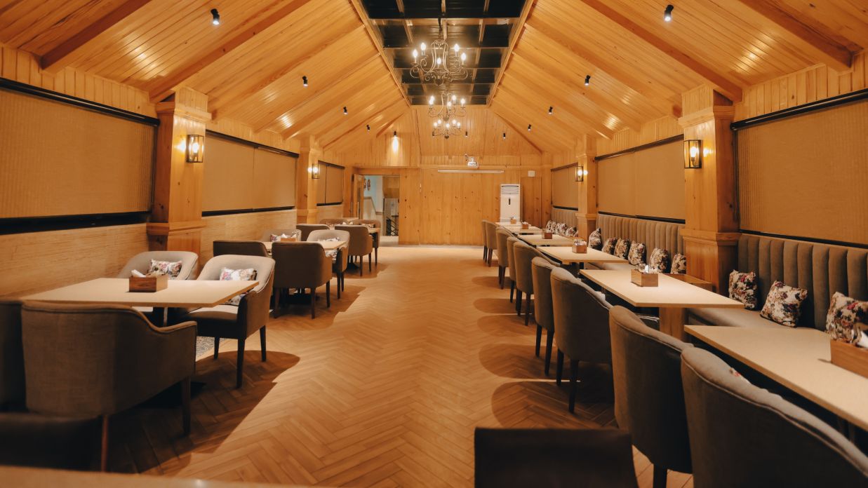 Clarks Inn Express Dehradun - interior view of the Clarks cafe featuring a wooden rood tables and an intricate chandelier