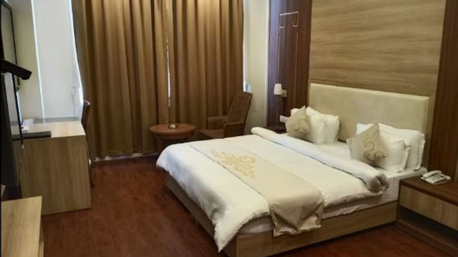 A queen bed with cushioned headboard and side tables inside Premium Room at Sumitel Gangtok l9noqs