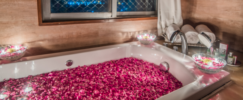 A filled bath tub at Sitara Luxury Hotel with rose petals and candles around it