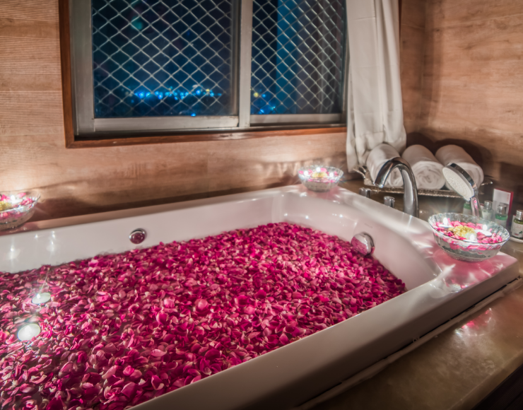 A filled bath tub at Sitara Luxury Hotel with rose petals and candles around it