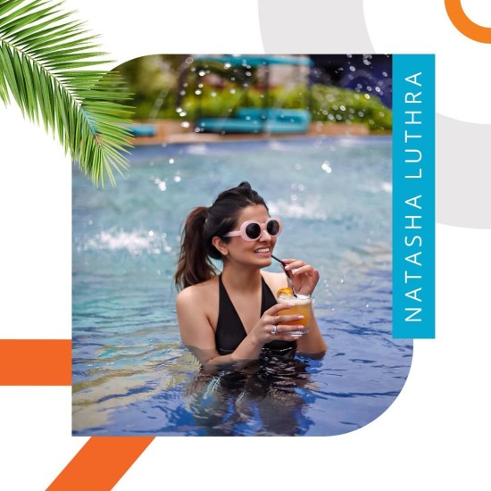 Woman with pink shades sipping a cocktail in a swimming pool