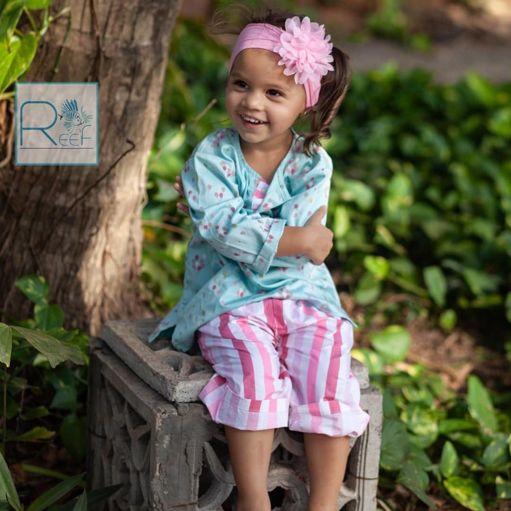 a toddler smiling and sitting with their hands folded