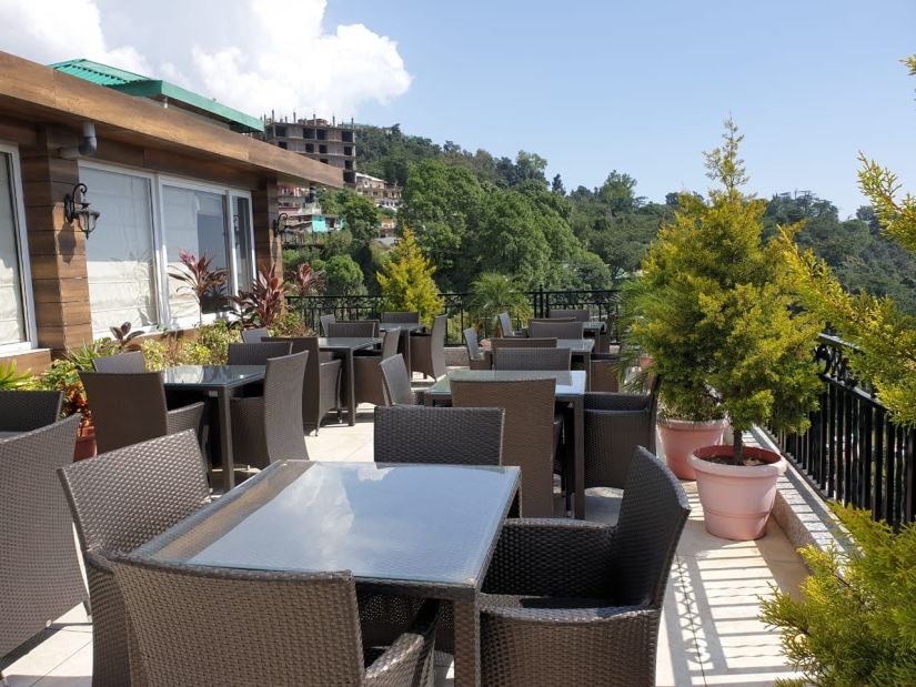 dining area on the terrace surrounded by lush greenery at Little Mastiff, Dharamshala