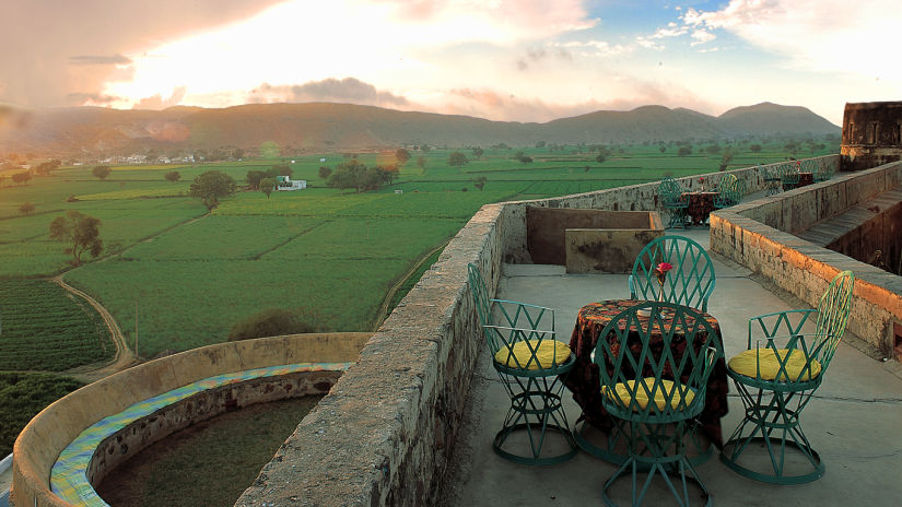 A table-chair set rests on the rooftop overlooking the cloudy sky