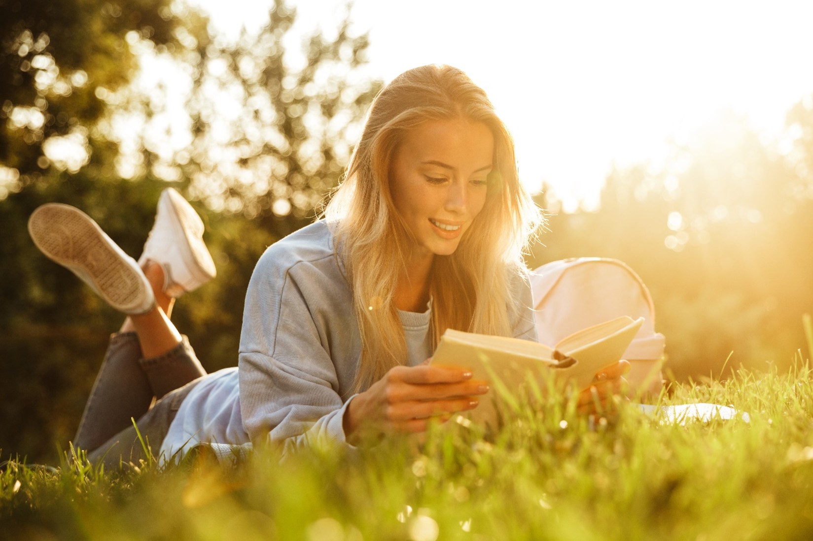 A woman reading a book lying down in a garden