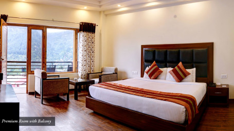 Premium room with bed and a glass door leading to the balcony at Summit Chandertal Regency Hotel & Spa