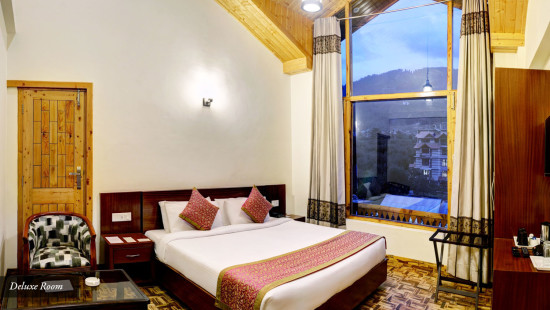 Side view of Deluxe room with large window and dressing table at Summit Chandertal Regency Hotel & Spa
