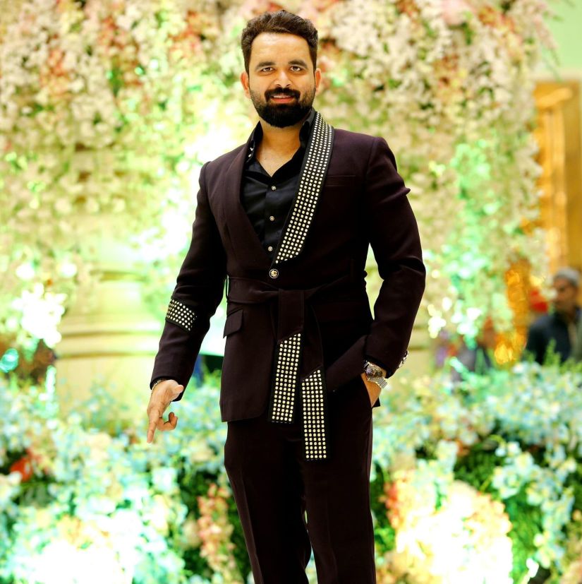 a man in black suit standing in front of a decorated background