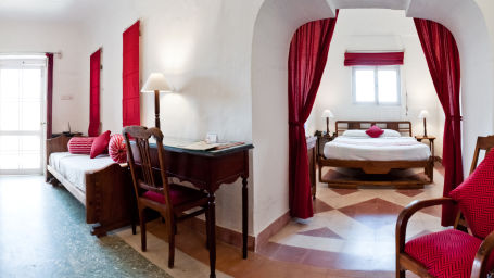 Hill Fort Kesroli 14th Century Alwar - interior view of the Shri Mahal with a king size bed and red curtains