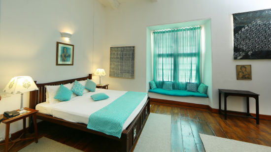 The Tower House - The Braganza room with light blue theme and features a queen size bed along with a large window and a lamp next to the bed