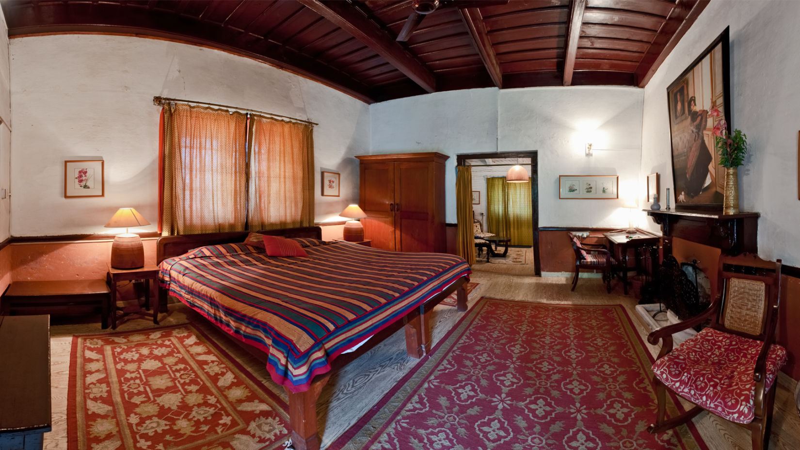 The Ramgarh Bungalows - full view of a room with cosy decor and carpeted floor along with wooden ceiling, a fireplace and a wardrobe