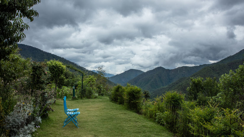 Scenic view of the Kumaon landscape filled with lush greenery and a chair demarked as a seating area