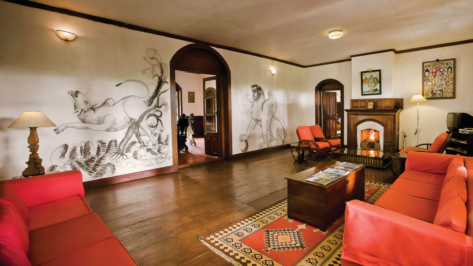 A living room showcasing red coloured sofas and a coffee table with drawings on the wall - Wallwood Garden - 19th Century, Coonoor