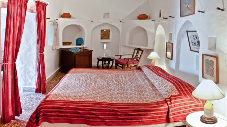 Hill Fort Kesroli 14th Century Alwar - interior view of the Bhawani Mahal with a king seize bed and red curtains