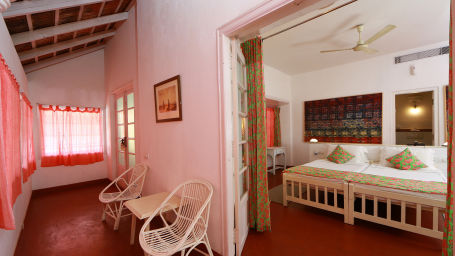 The Tower House - The Cunes Room with two single beds joined together and a verandah and red curtains with two chairs 