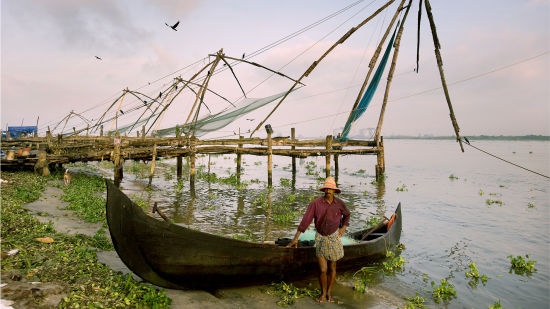 an image of chinese fishing net being used with a fisherman standing next to a boat