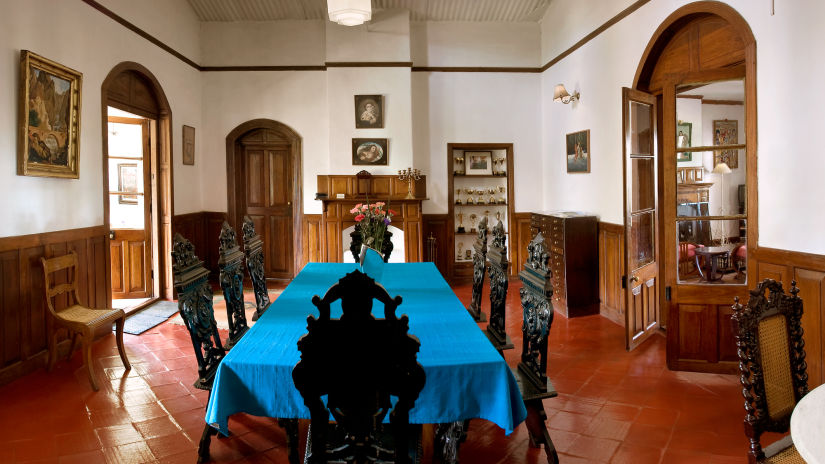 A large dining table with blue cloth covering and beautifully carved wooden chairs next to it - Wallwood Garden - 19th Century, Coonoor