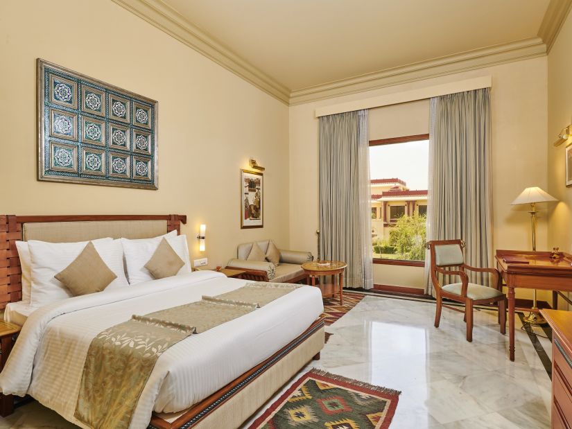 a deluxe room with king size bed featuring soft white linens and a window offering great view - The Ummed Jodhpur, Palace Resort and Spa