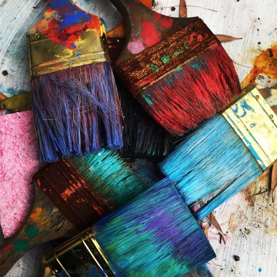 An overhead shot of 6 paint brushes dipped in colour