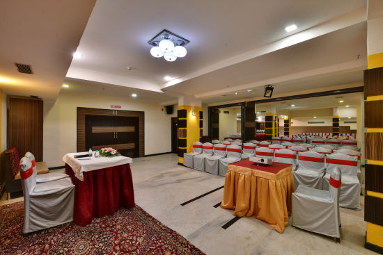 alt-text Another view of a grand banquet hall with a table and elegant chair arrangements - Click Hotel Yuvraj, Surat