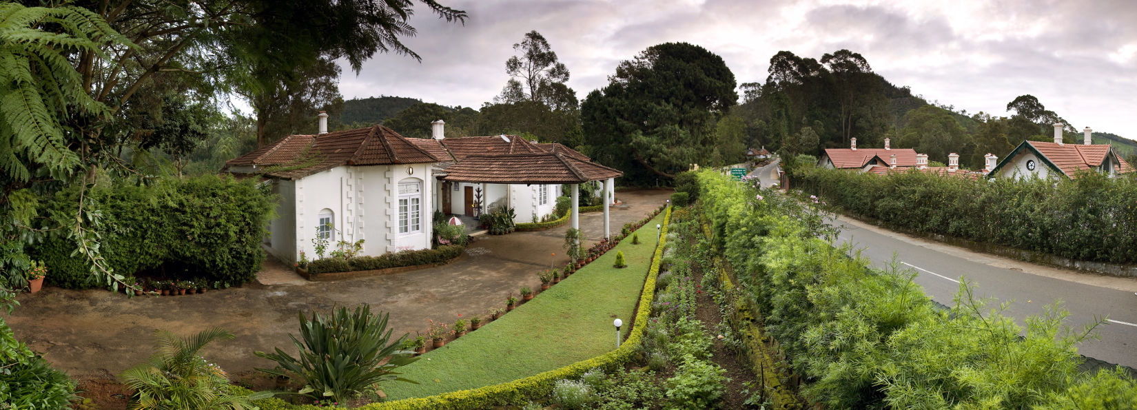 Side view of the facade and the road next to the hotel with greenery in the centre - Wallwood Garden - 19th Century, Coonoor