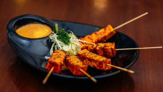 Paneer Tikka served on a black plate with salad